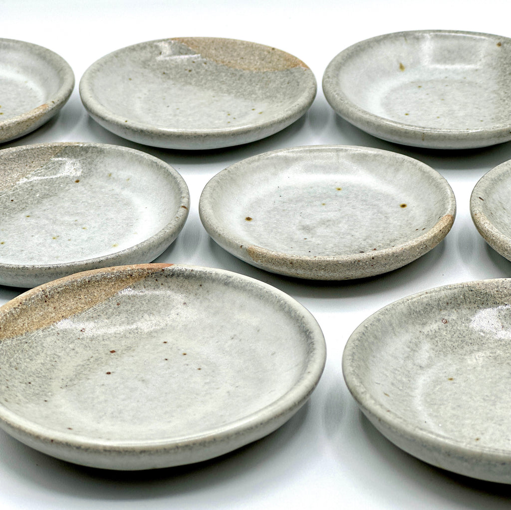 This photo is of a group shot of the  hand crafted, small, white and grey ceramic sea salt dishes.